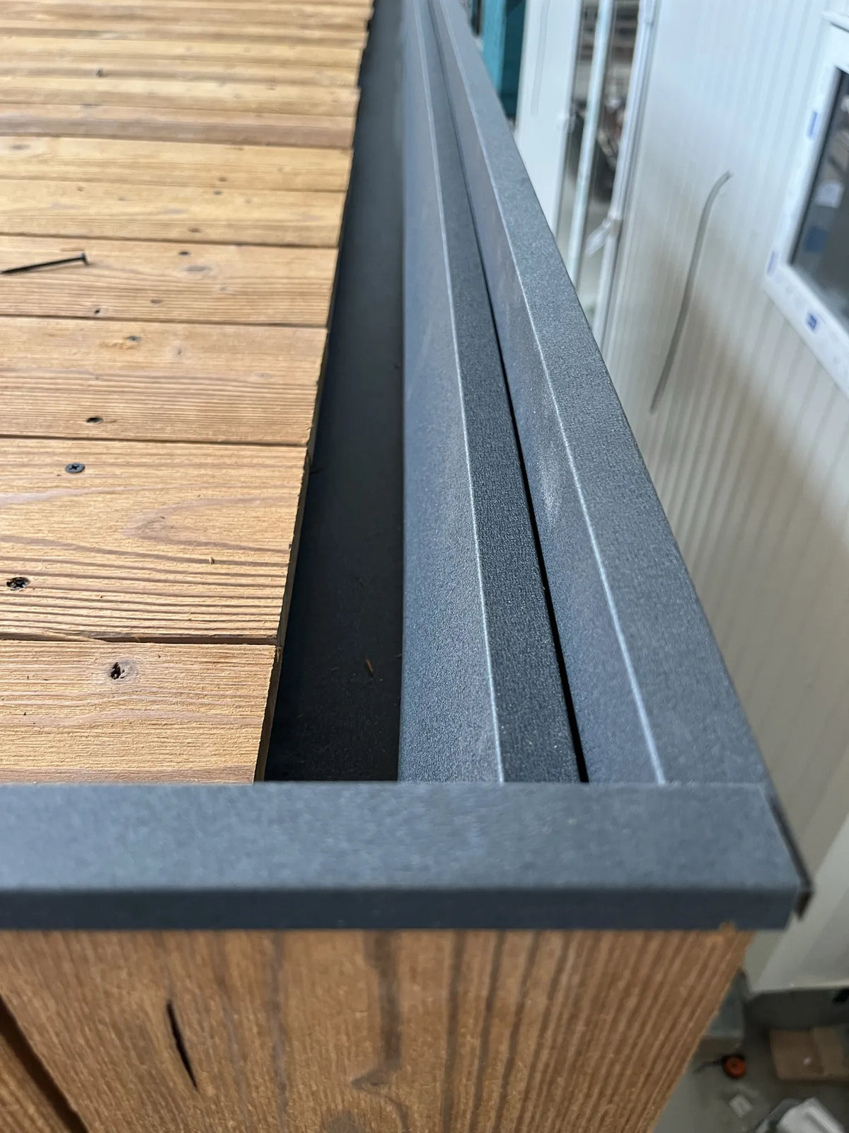 The roof edge of a NOOK 10 in production: timber boards, a drainage channel and a black trim