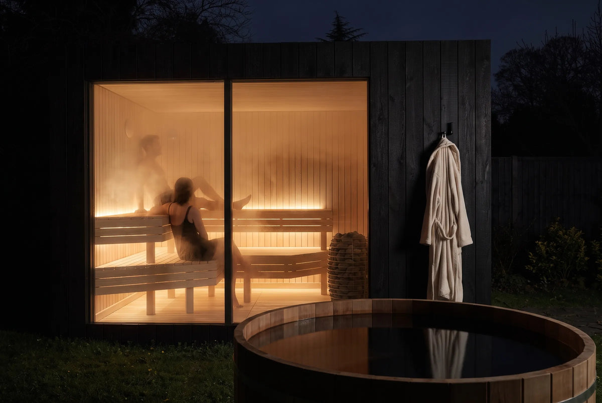 Visualisation of a NOOK Sauna lit at night, two people inside, a robe hanging on the wall and a cold plunge in front